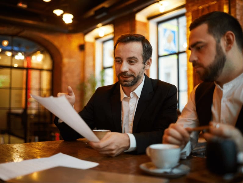 Two business people working in cafe discussing documents.