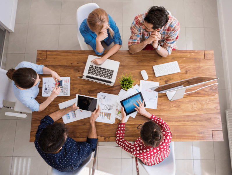 Arial view of team sitting around table discussing scope management