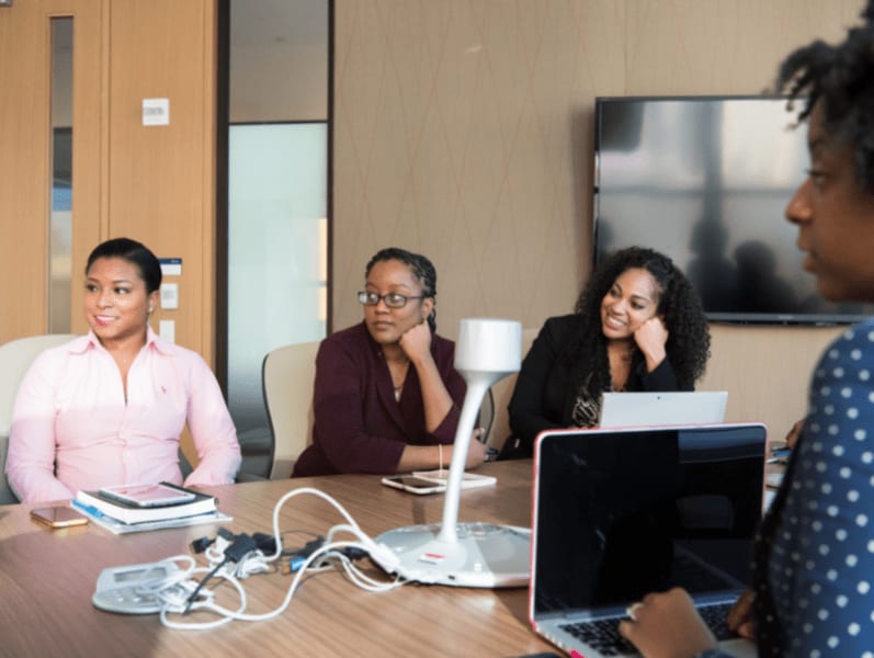 Female colleagues sitting at board table reviewing fair prices for consulting