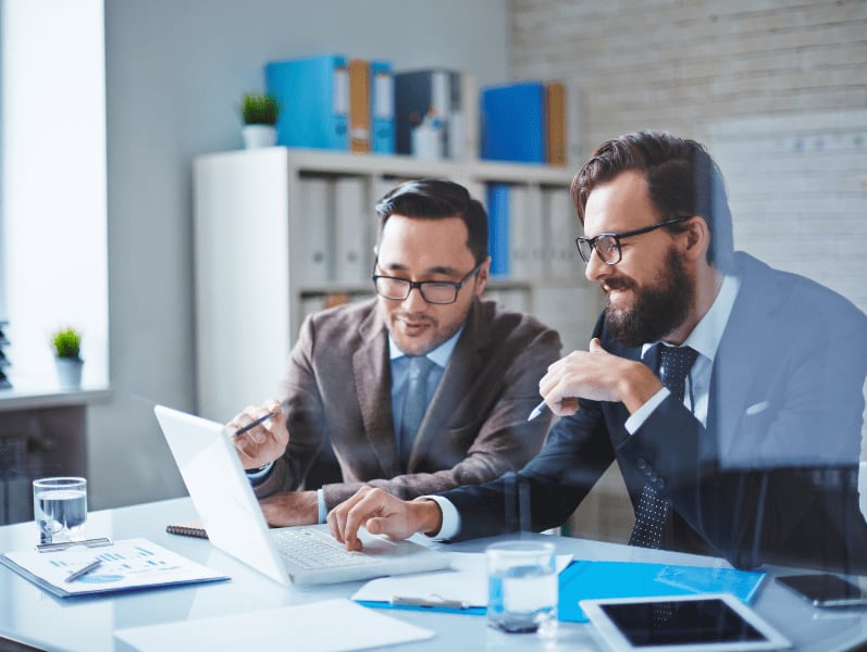 Two male colleagues sitting in front of laptop review consulting engagements