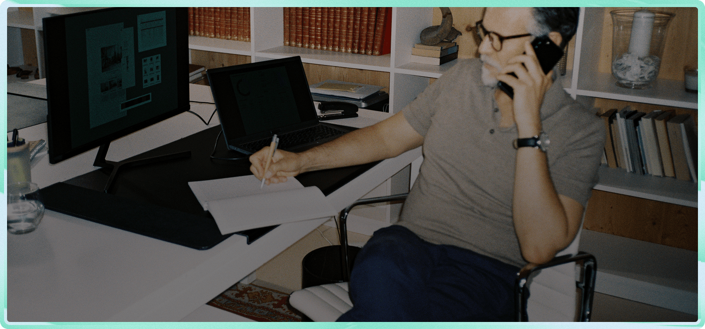 A business owner takes a call at their desk while reviewing paperwork