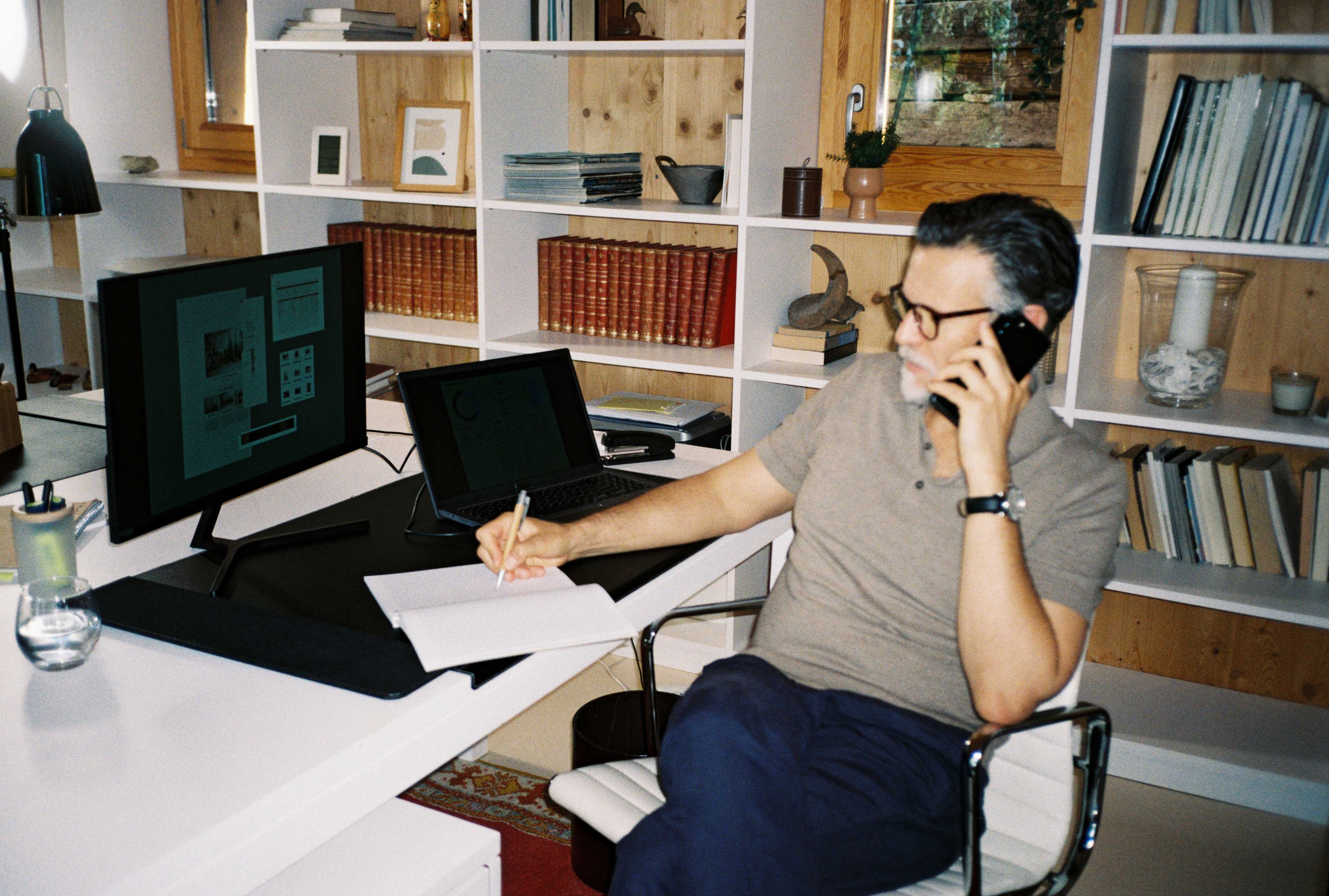 A business owner takes a call at their desk while reviewing paperwork